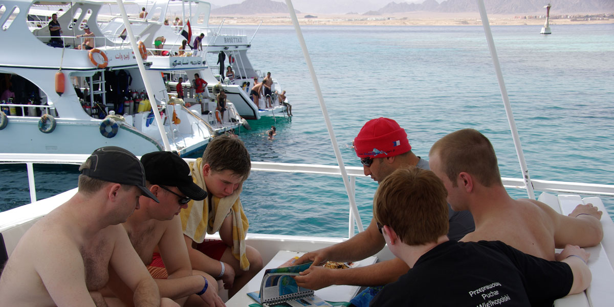 kursanci z instruktorem przy stole na statku nurkowym w egipcie